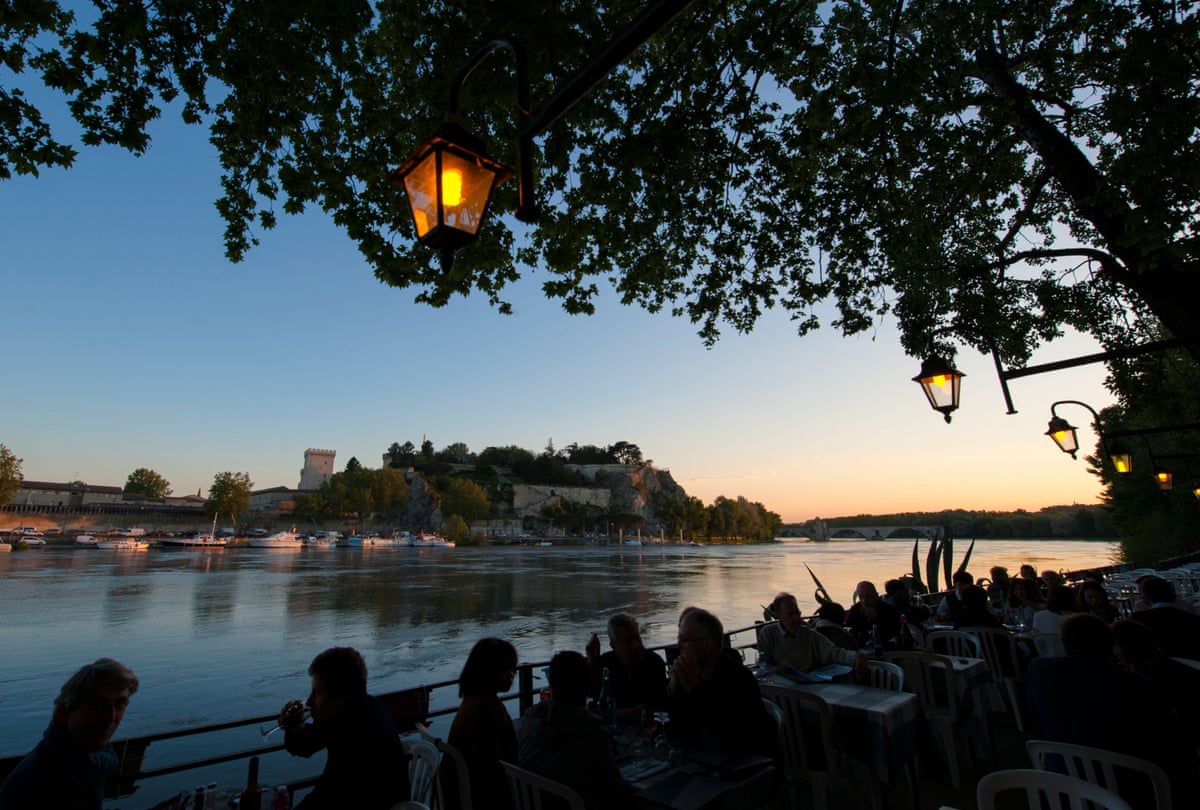 Evening view over the Rhône river with diners in the foreground.