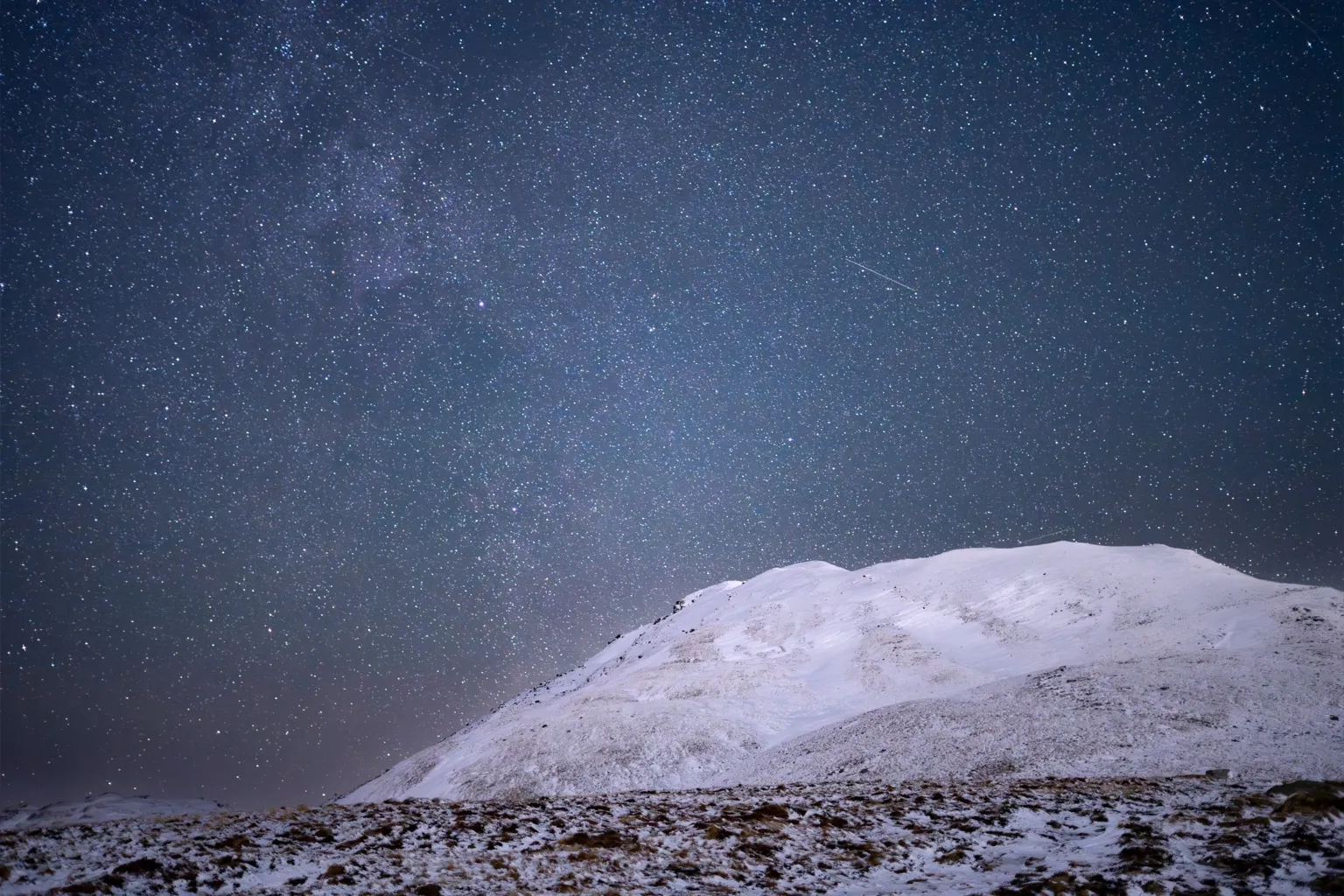 David Currie Ben Lomond is covered in snow beneath a starry night sky. 