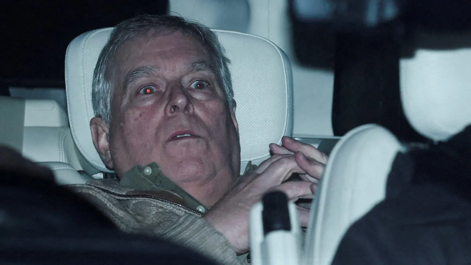 /Phil Noble A shocked Andrew leaning back on a car seat, his eyes reflecting the photographers' flashes in the red-eye effect and his hands clasped steeple-like