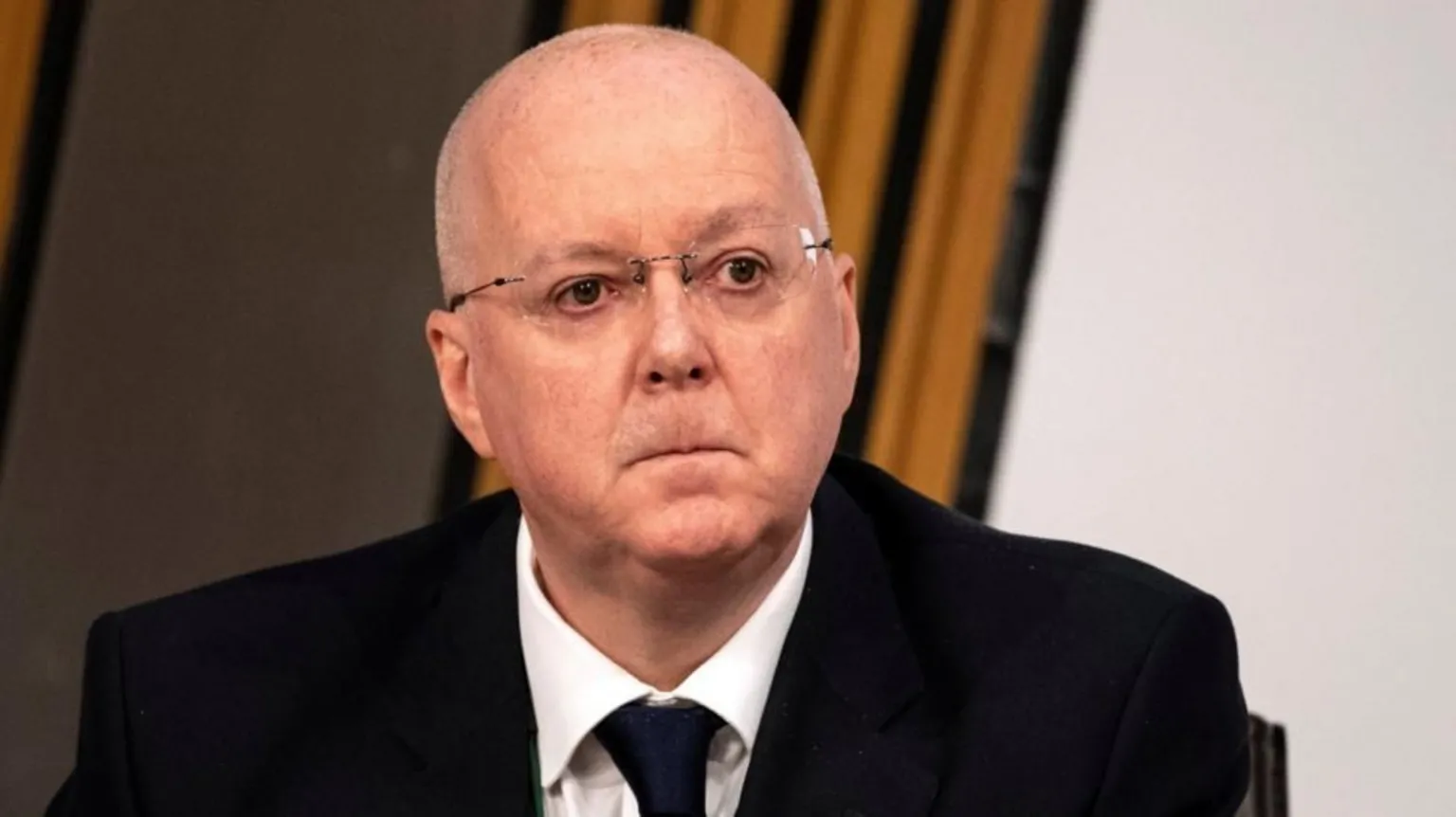  Peter Murrell - a bald man with glasses, wearing a dark suit and tie - pictured looking solemn during a Scottish Parliament committee meeting in 2021