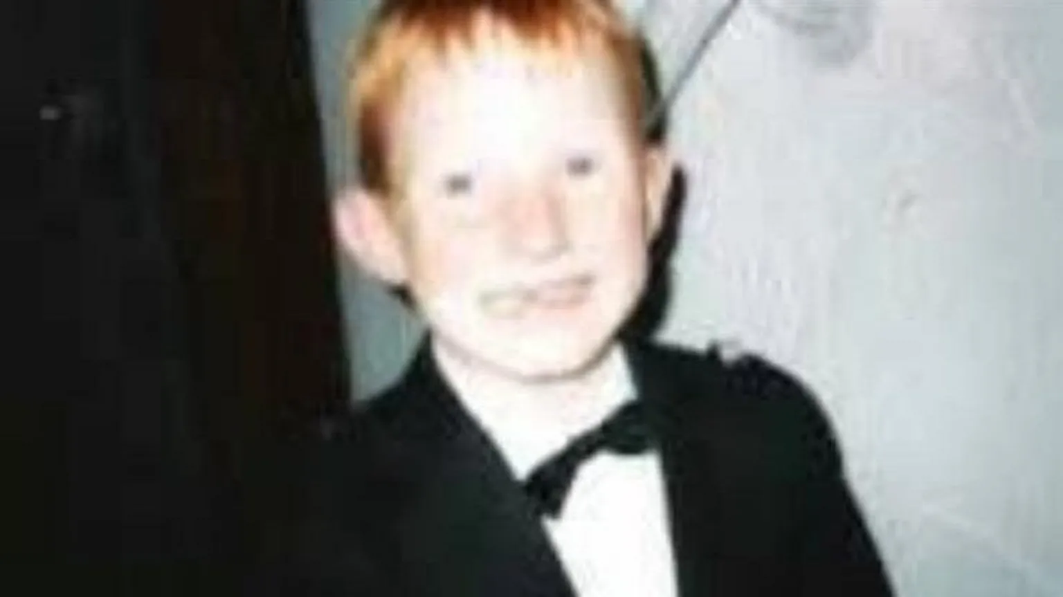 White family Grainy picture of a grinning schoolboy with short red hair. He is wearing a black suit jacket, white shirt and black bow tie 