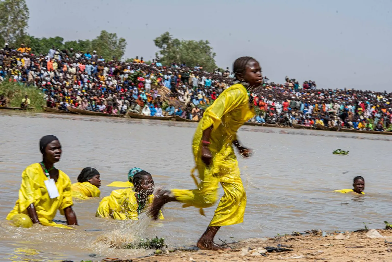 Sani Maikatanga Girls in yellow uniforms emerge from the water after having tried to catch some fish.