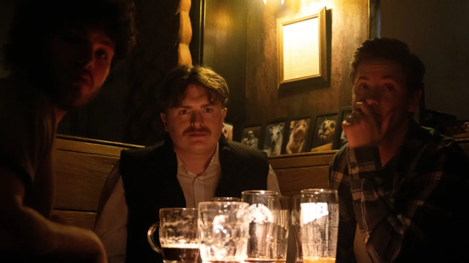 Nathan and Ben McQuaid Three men sit round a table in a dimly-lit pub with beer glasses on a table in front of them