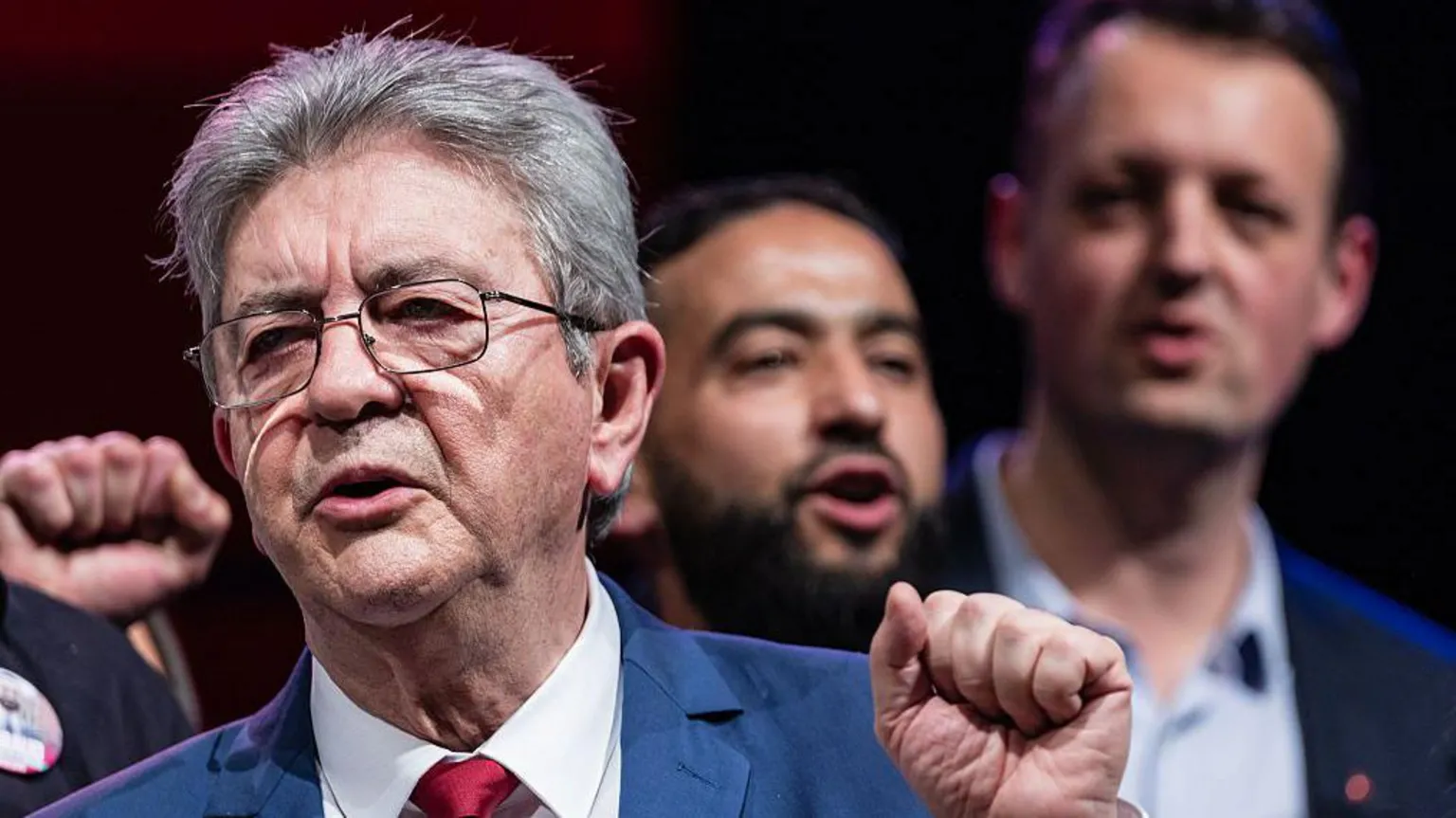 AFP via A man holds up his fist wearing glasses and a light blue suit