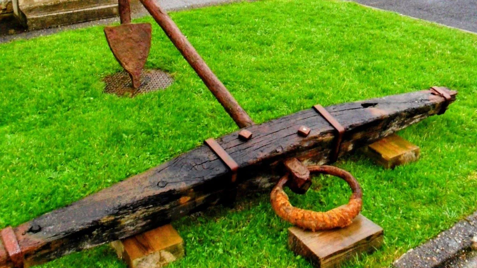 Anne Cadwallader A large wooden and metal anchor on display on a grassy bank 