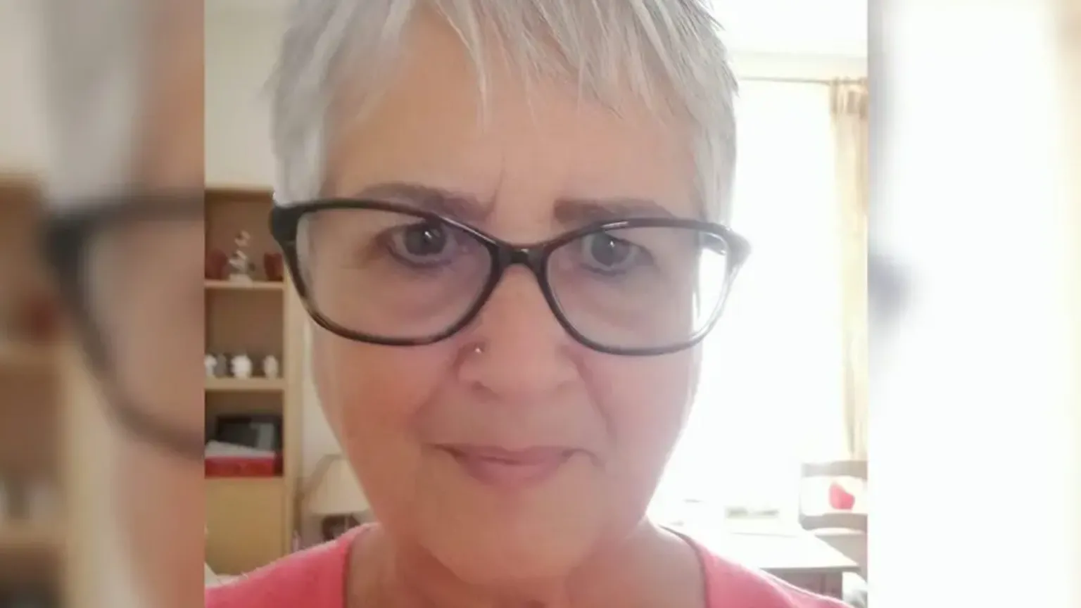 Family photo Photograph selfie of Judith Rhead. She has silver short hair- and wears black wide rimmed glasses. She has brown eyes and looks into the camera. 