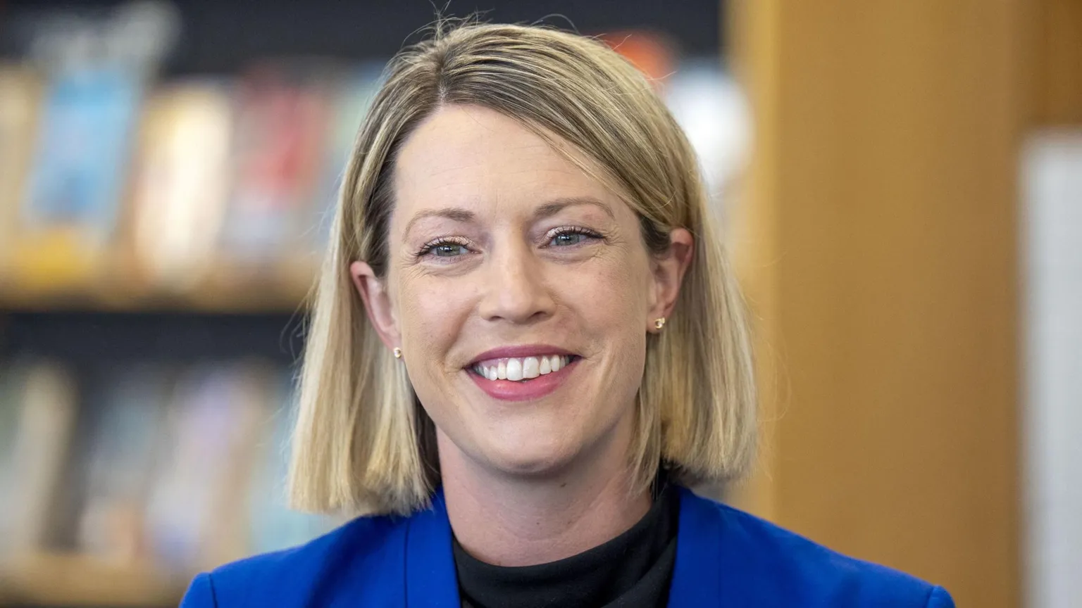 Jenny Gilruth has shoulder length blonde hair and smiles. She wears a blue blazer and black top