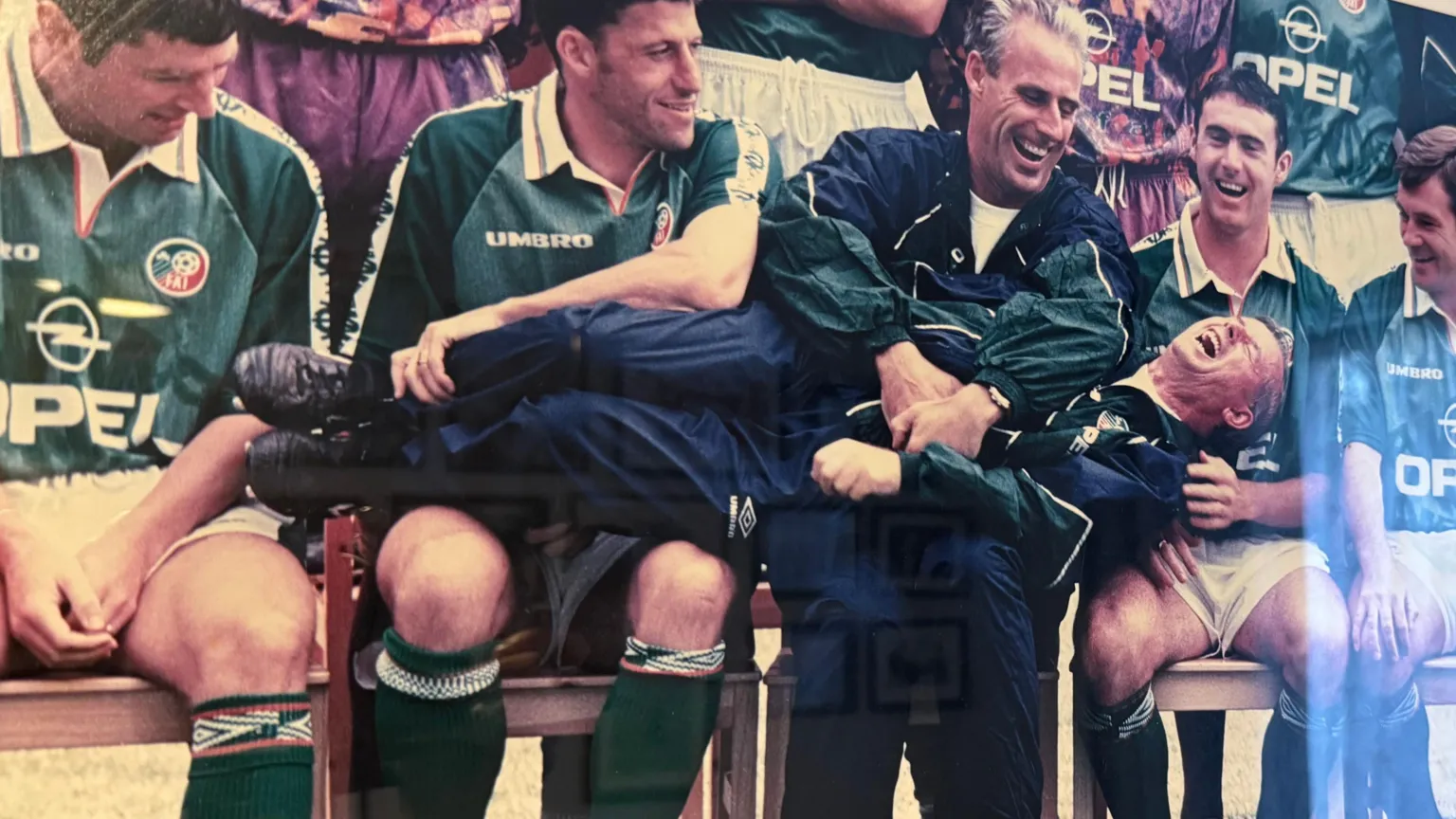 O'Leary family A photo of the 1990s Republic of Ireland team - four players and manager Mick McCarthy are sitting down for a team photo and Charlie O'Leary lies across them as McCarthy tickles him and he laughs. The players are wearing dark green shirts while McCarthy and O'Leary are in dark blue tracksuits with green arms.