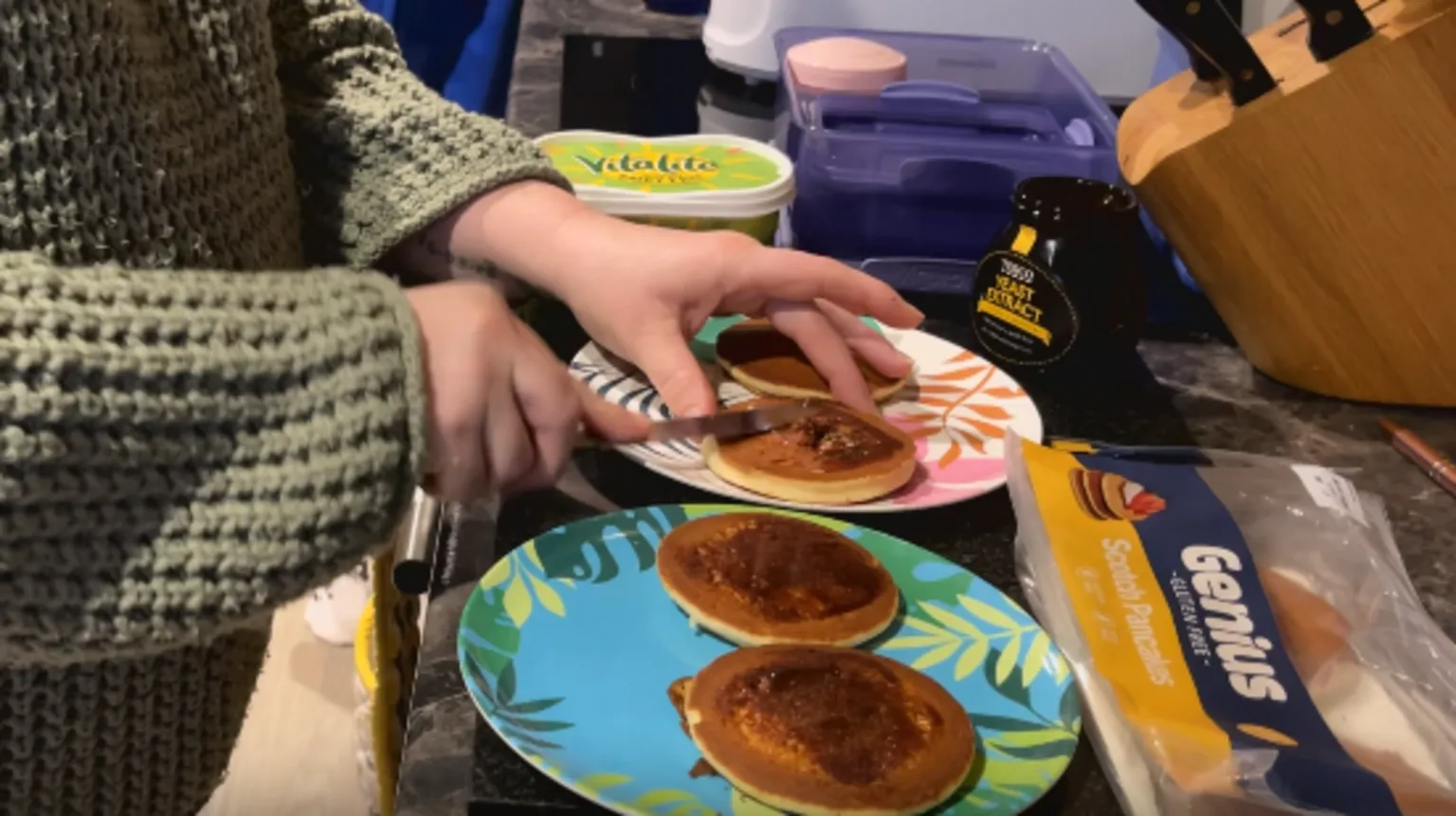 Alex Osborne/ BBC Image shows Debbie making the childrens' breakfast; two colourful plates topped with small, round pancakes, spread with marmite.