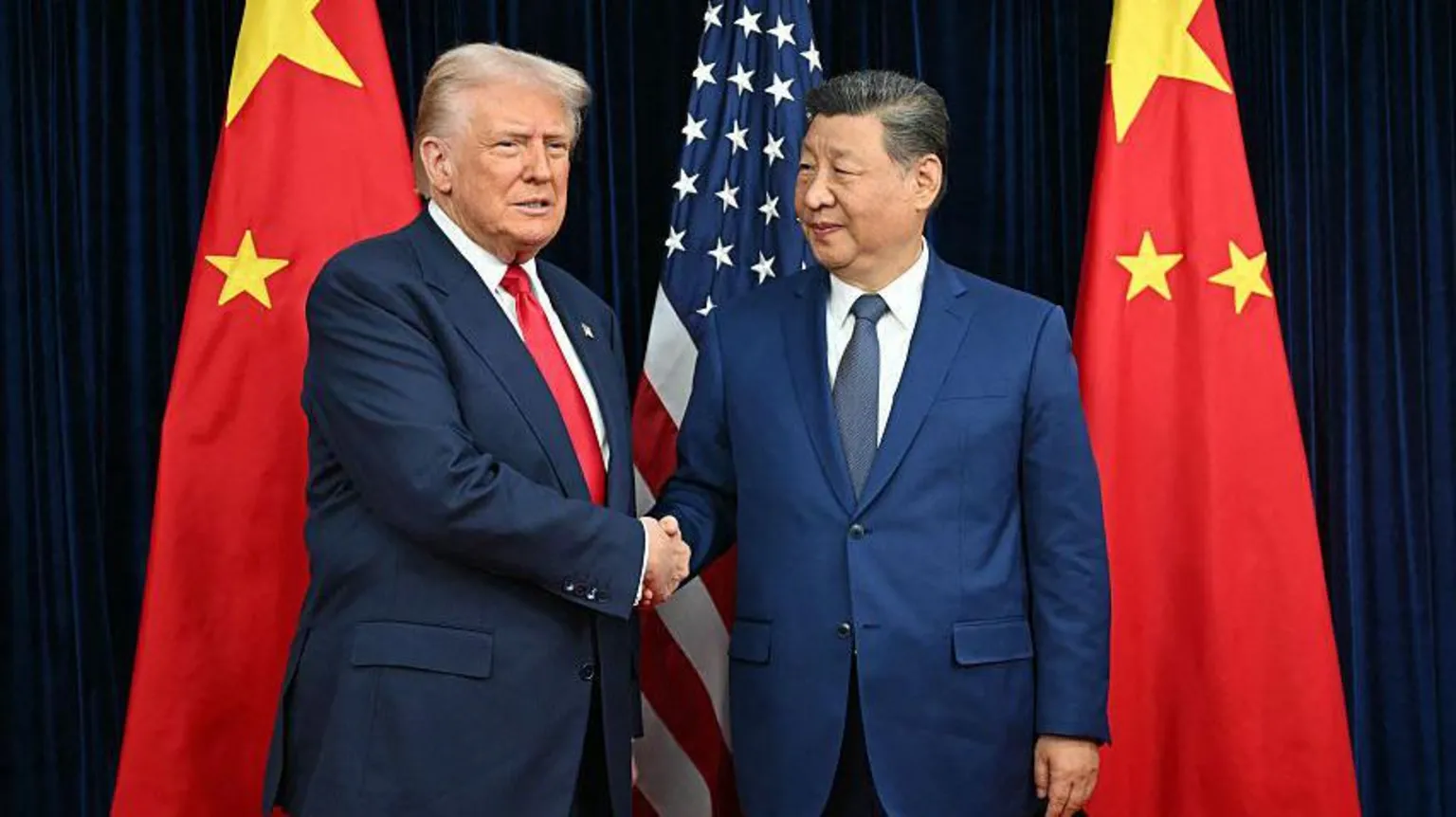 US President Donald Trump (left) and China's President Xi Jinping shake hands in front of the American and Chinese flags