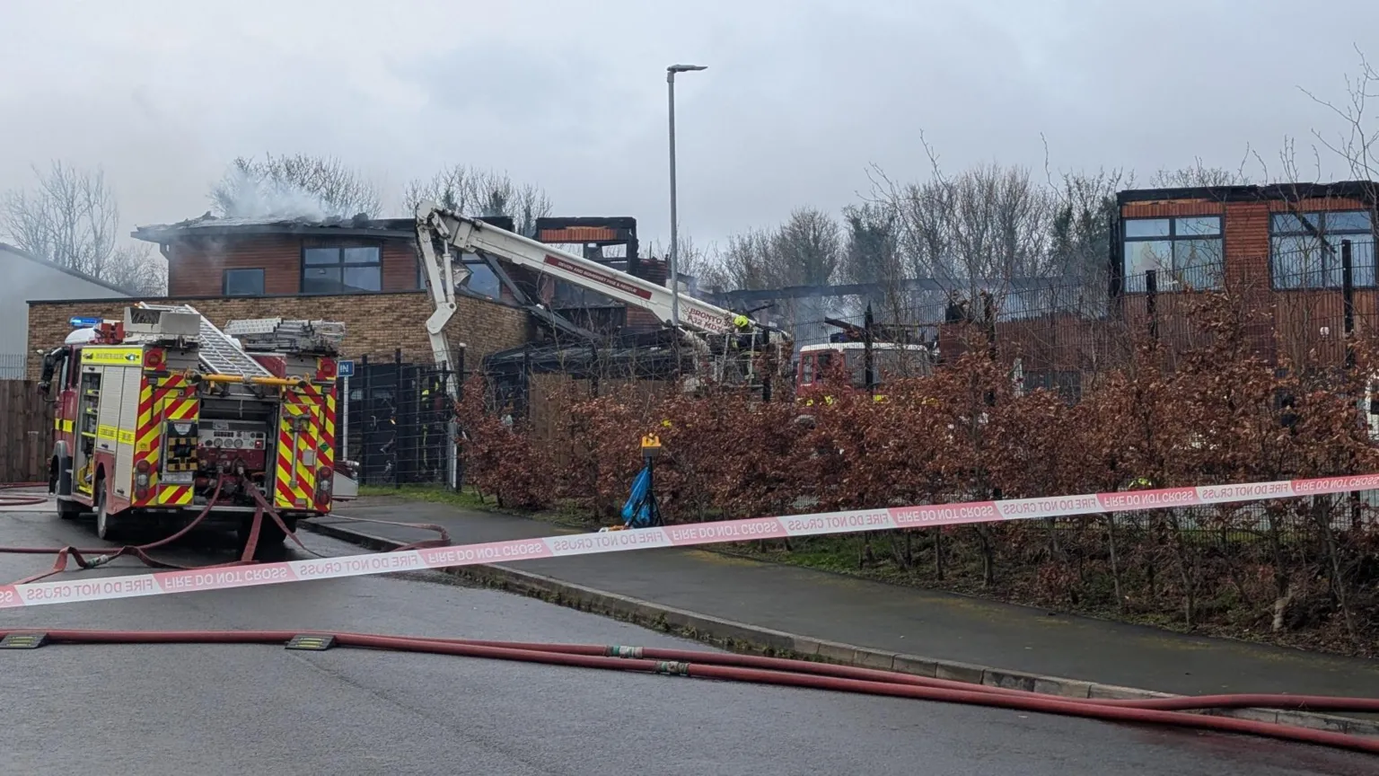 Firefighters continue to tackle flames at the scene of a blaze at a school in Devon. The area has been cordoned off with red and white tape.