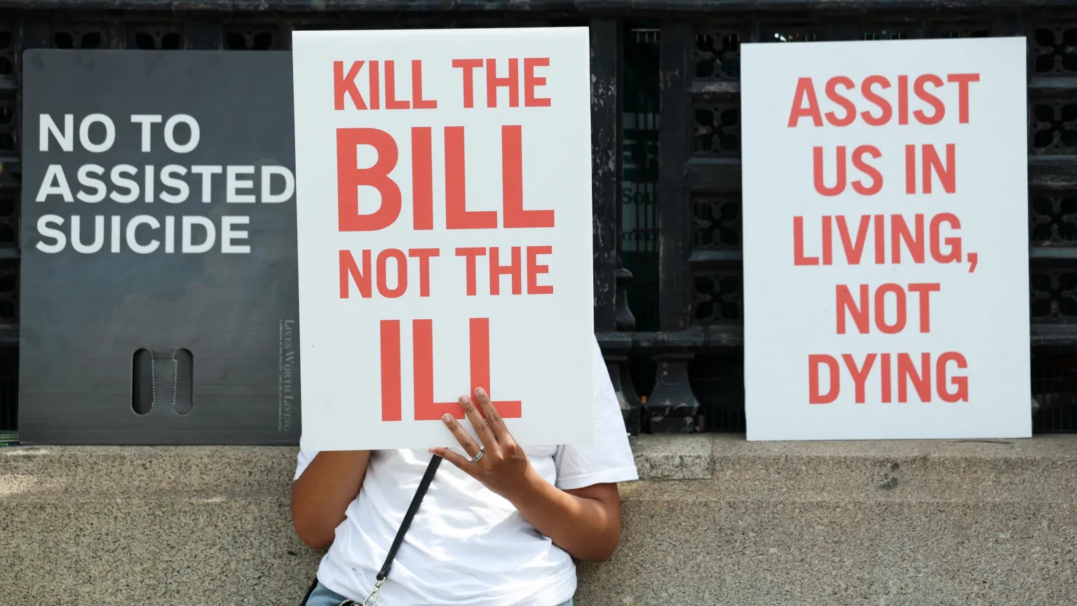 A protest with a person obscured by a placard which reads