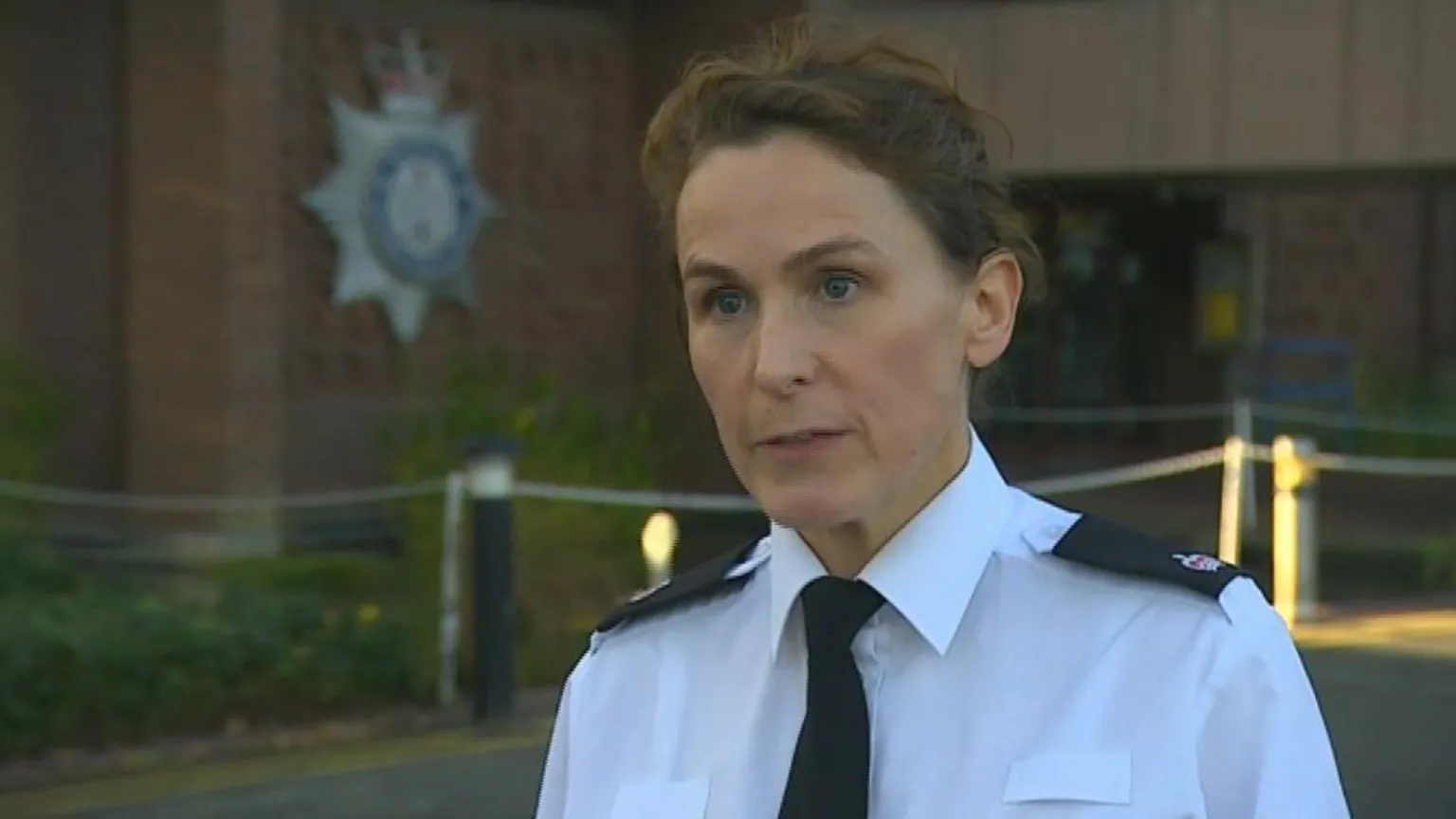 Det Ch Supt Jane Topping during an interview. She is standing outside Suffolk Police headquarters. She has short brown hair and wears a white shirt with a black tie and black lapels on the shoulders. 