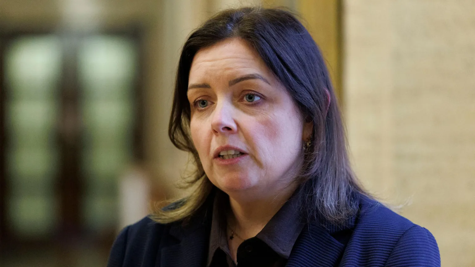  Deirdre Hargey is standing in Stormont's Great Hall. She has dark hair and is wearing a navy jacket. 