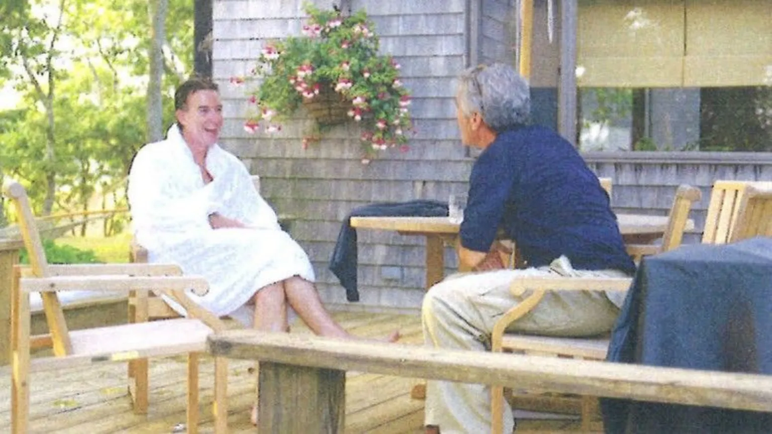 HOUSE OVERSIGHT COMMITTEE A copy of an undated picture of Peter Mandelson sitting in a white robe laughing while sitting opposite Jeffrey Epstein, who wears a blue top and cream chinos, on a wooden deck.