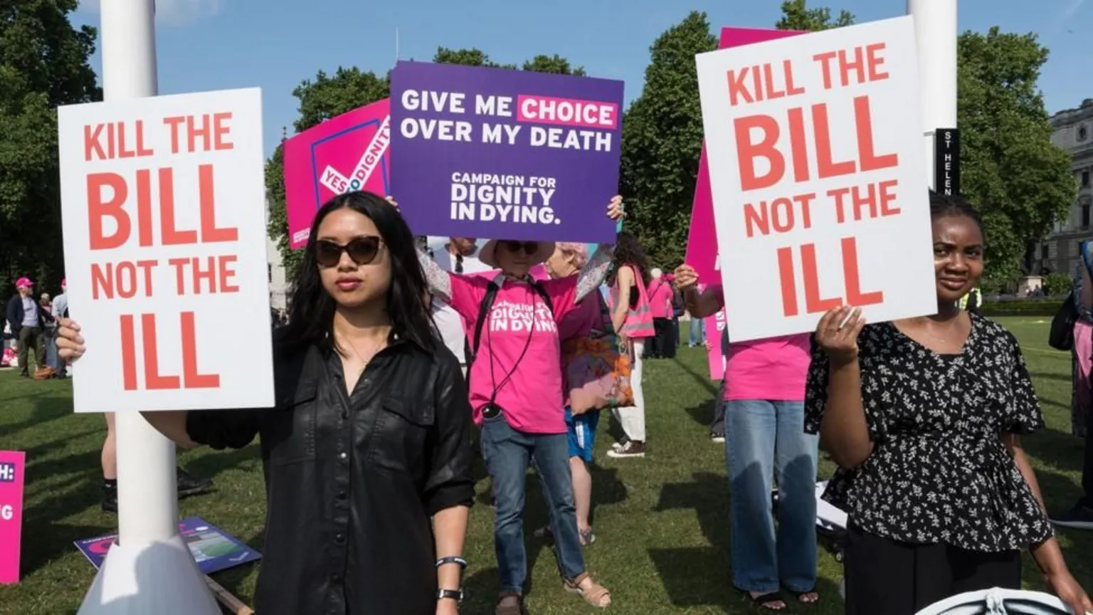 Future Publishing via People hold up placards on a grassy field, some supporting an assisted dying law and others opposing one.