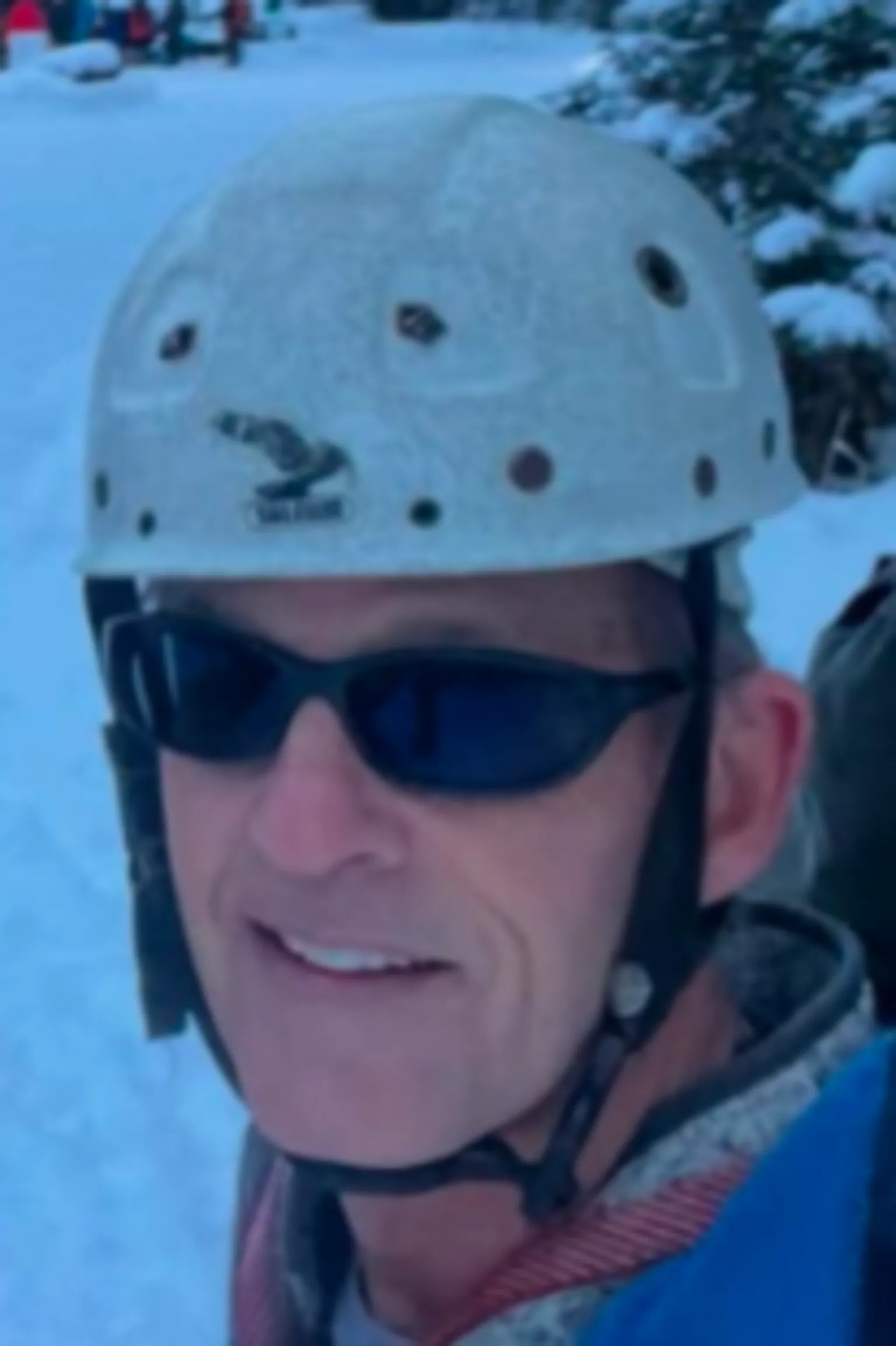 Police Scotland Close-up of a man wearing a white climbing helmet and dark sunglasses, standing outdoors in a snowy setting.
