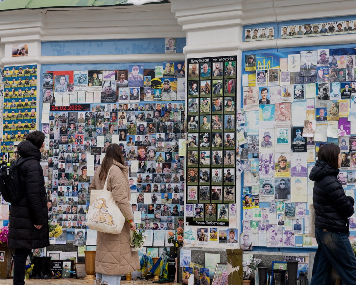 People holding flowers pay their respect as they look at the Wall of Remembrance of the Fallen for Ukraine in Kyiv, Ukraine.