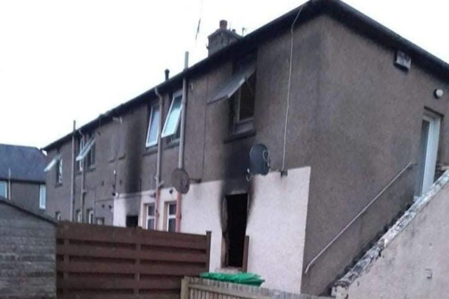 Becky Young A burned out two-storey property, taken from behind a garden fence. 
