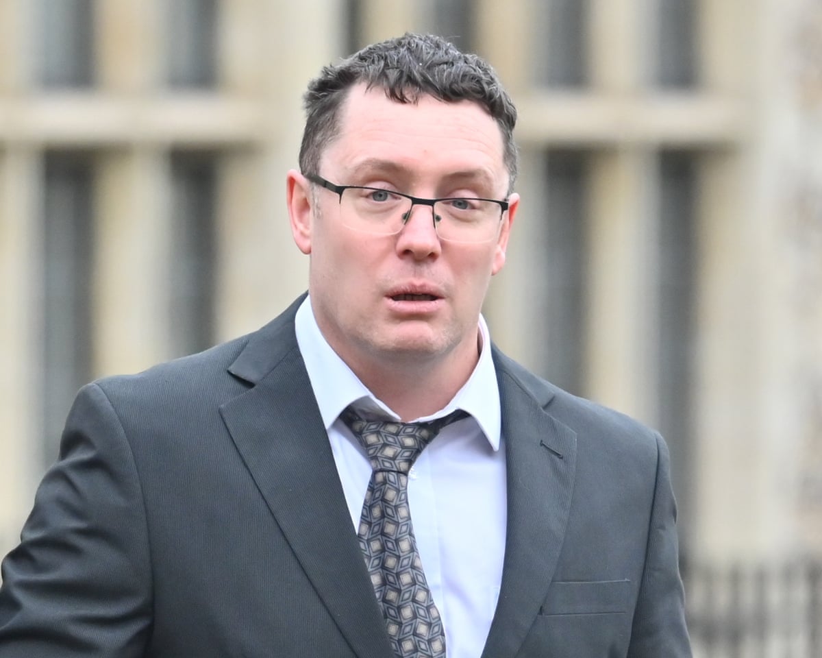 Christopher Trybus in grey suit looking stressed