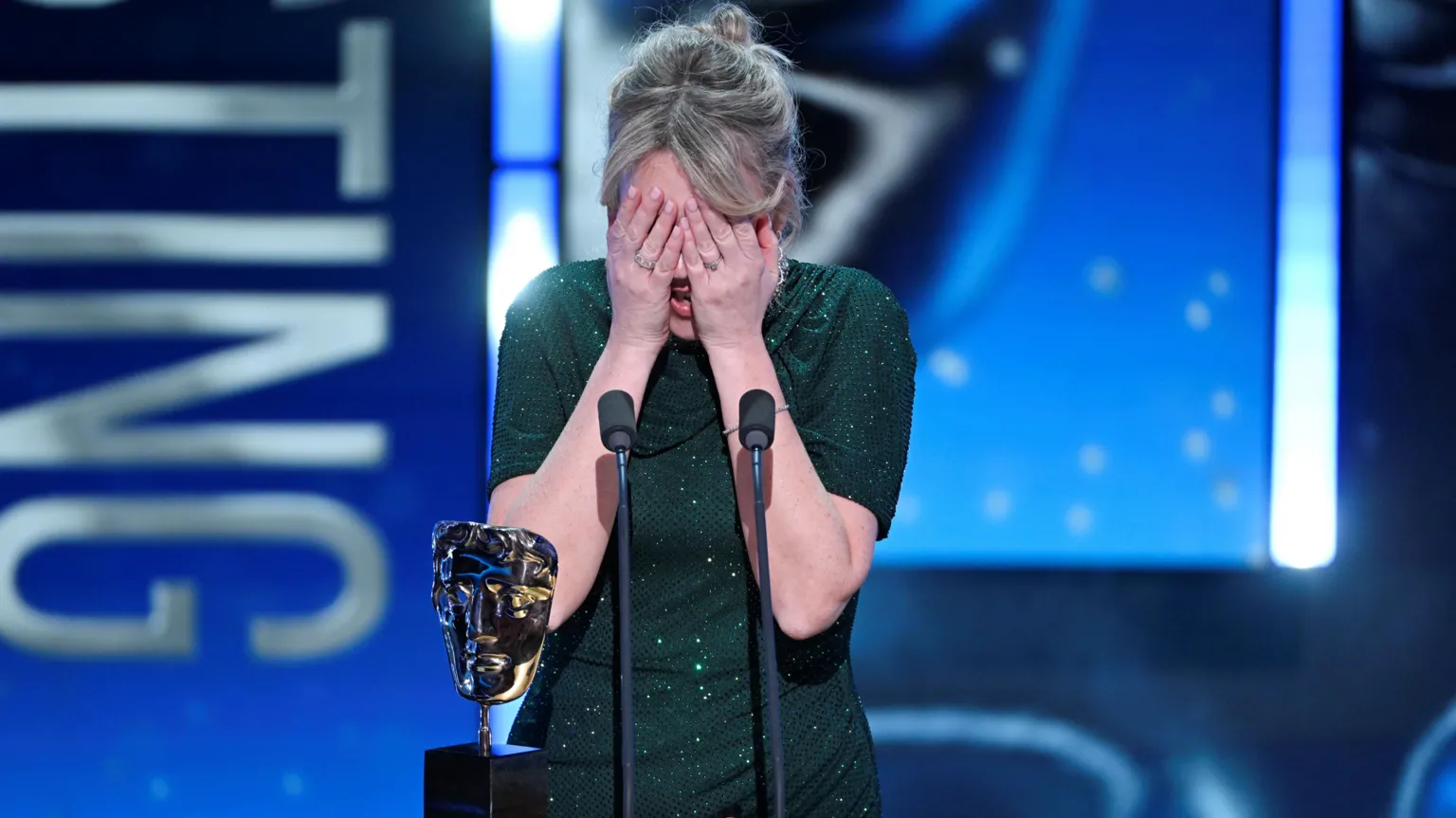  Evans on stage accepting her award. Her hands cover her face