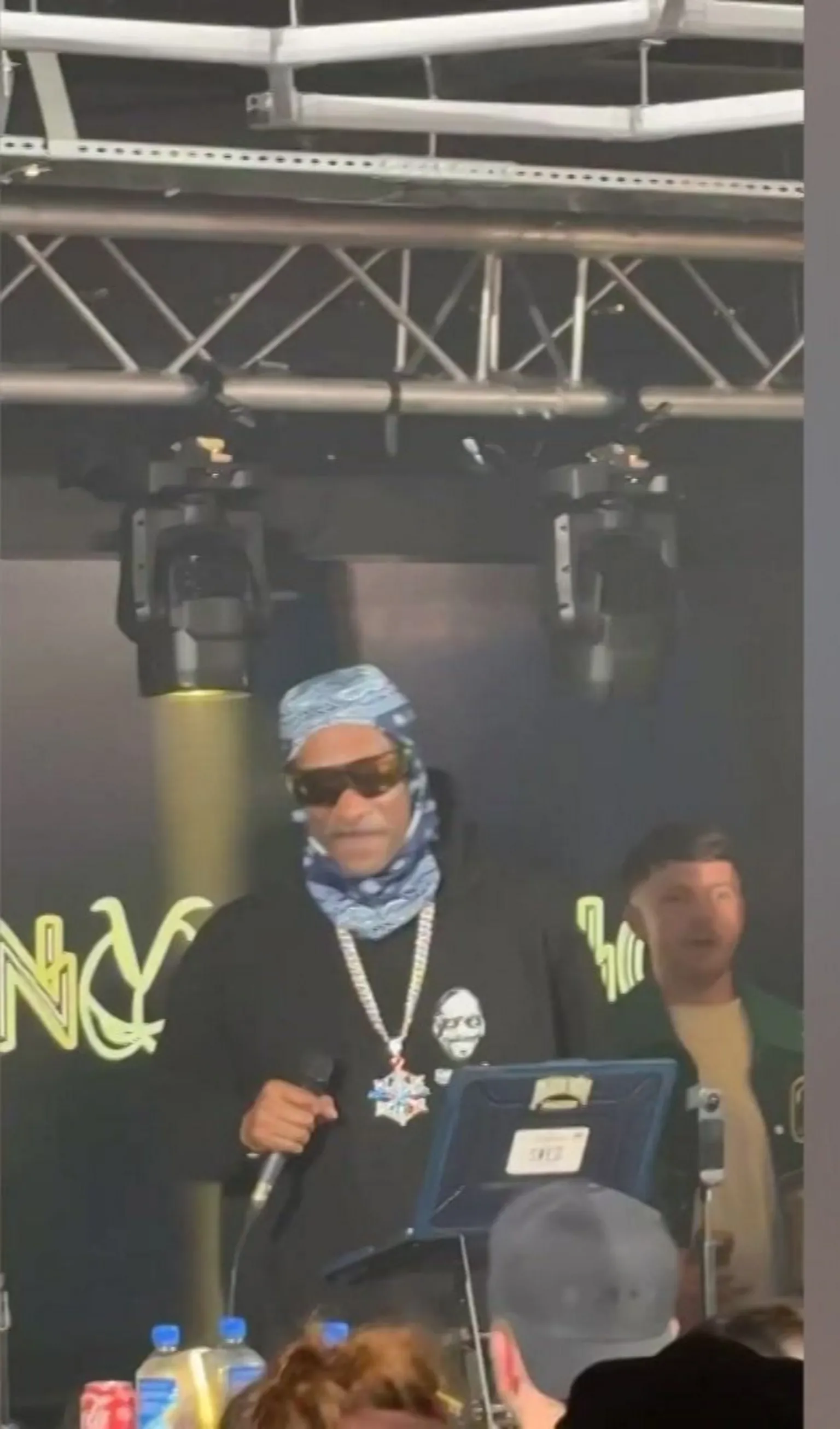 Au Vodka Mobile phone image of Snoop Dogg, in sunglasses and wearing a sweat top and head covering, performing as DJ at an office in Swansea, the headquarters of Au Vodka