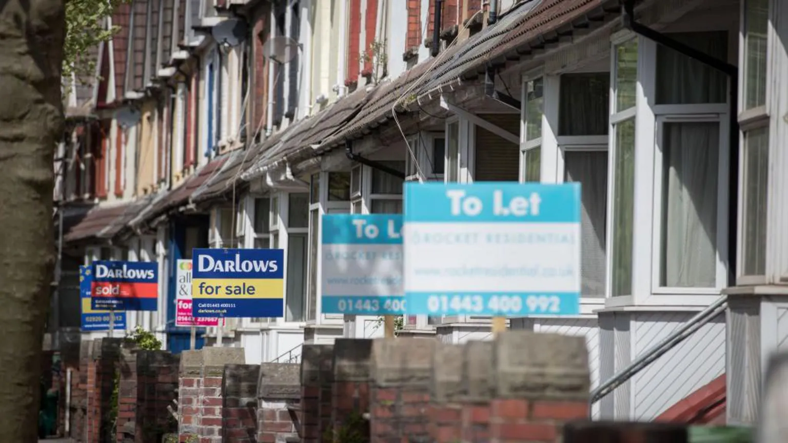  A series of houses for sale and rent with estate agent signs in anonymous street