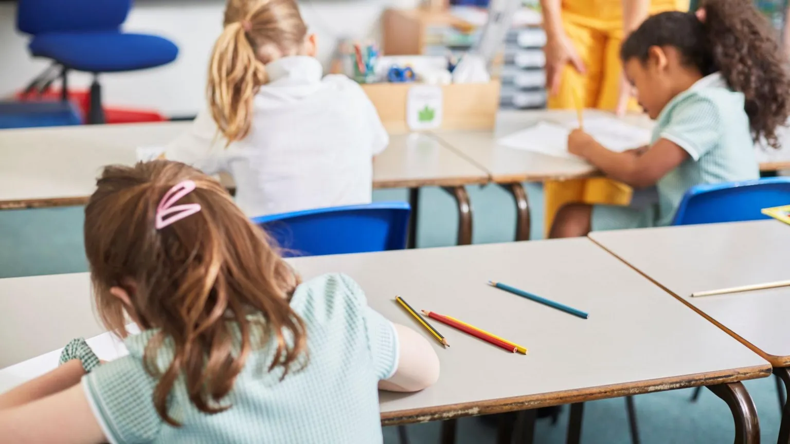  A stock image of school pupils sitting at their desks working. The pupils are all girls, and are pictured from behind.