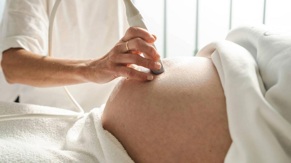 Doctor yn sganio bol merch feichiog