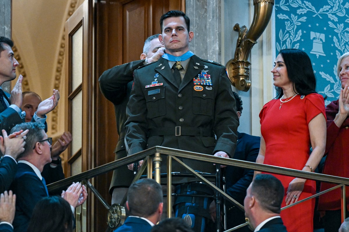 US Army Chief Warrant Officer Eric Slover stood up while a medal is tied around his neck to applause.