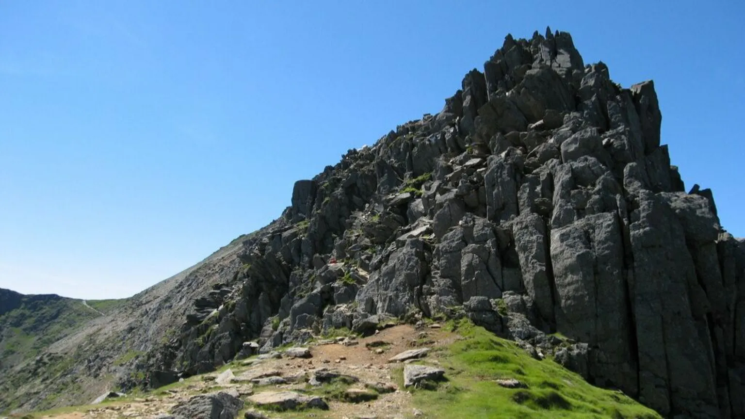 Geograph/Dave Croker Crib y Ddysgl - a rocky mountain ridge jutting into the air, with a blue sky behind. 