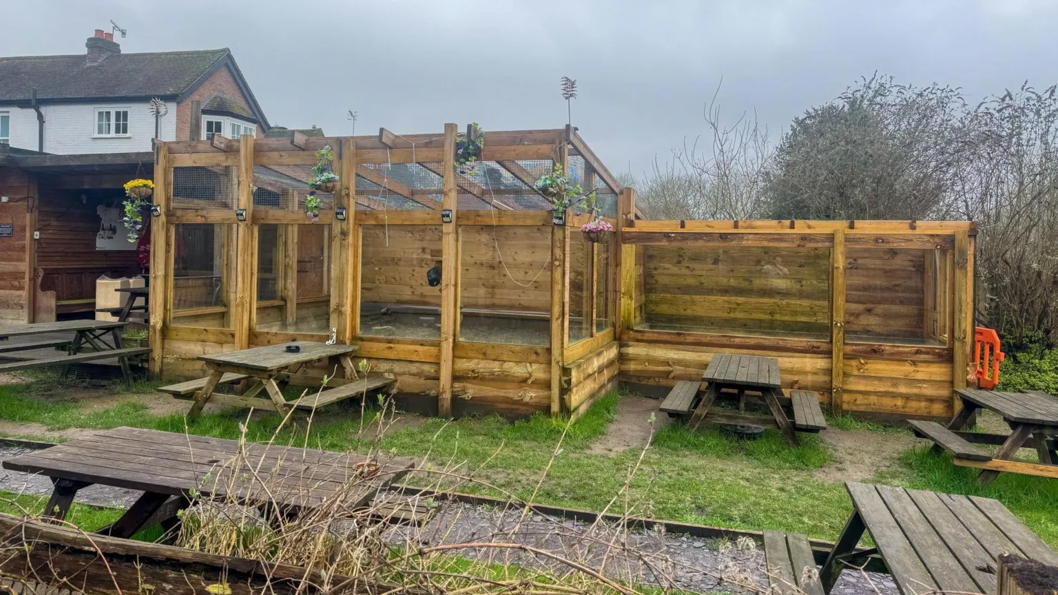 Geoff Robinson The meerkat enclosure at the Royal Oak Inn and Meerkat Retreat in Brockham, Surrey. The enclosure is made of wood. Picnic tables sit beside the enclosure.