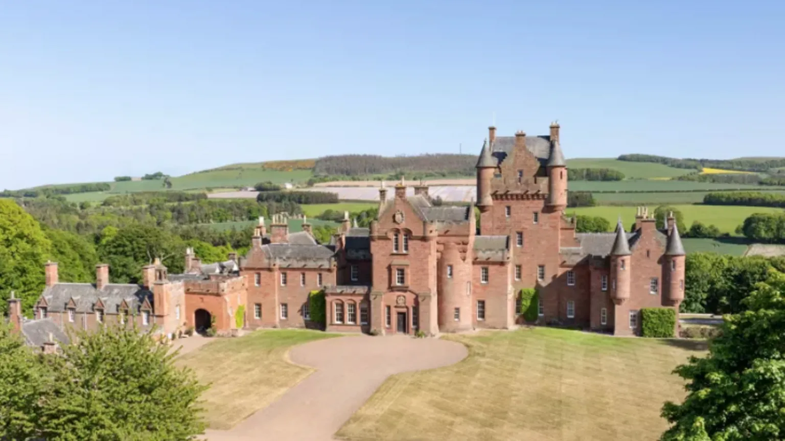 Knight Frank A long distance view of Ayton Castle a grand building surrounded by hills and trees