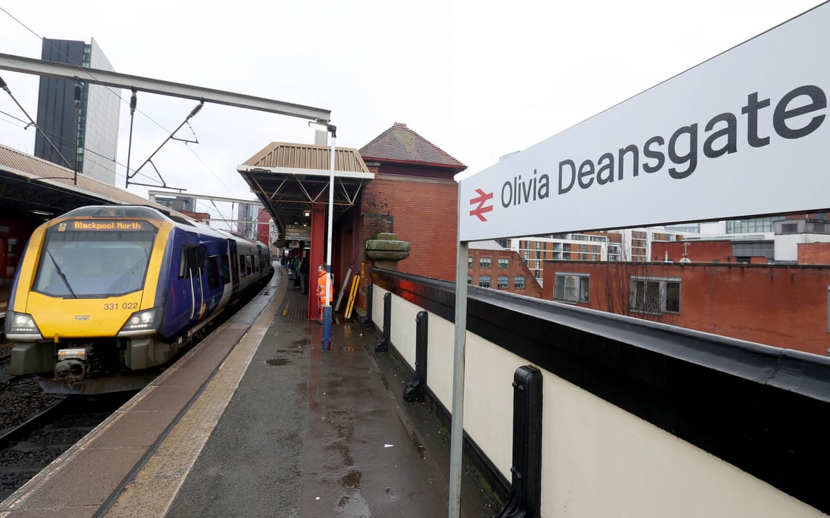 A train pulls into a platform with the sign ‘Olivia Deansgate’.