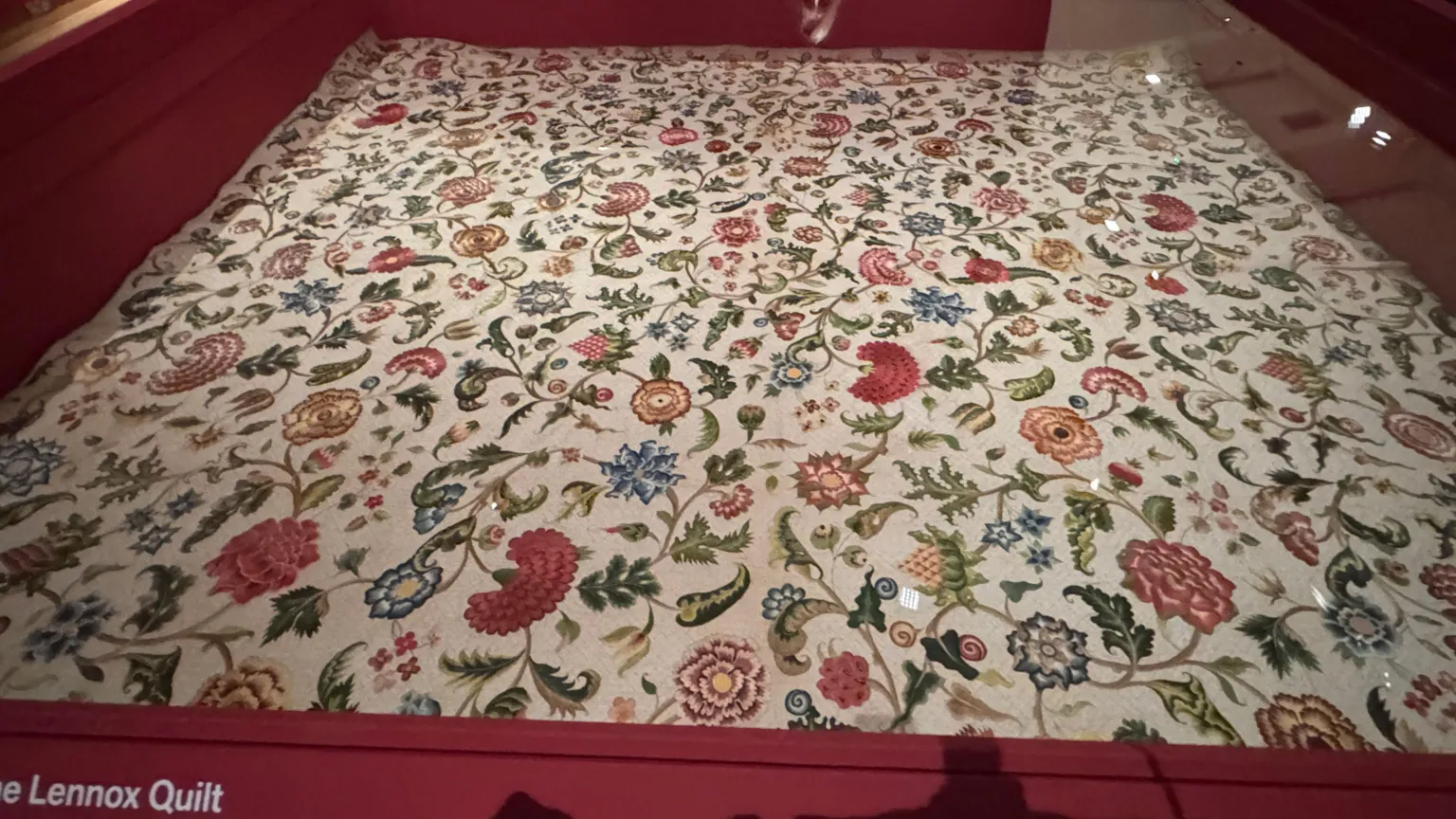 A quilt on display. It has floral designs. 