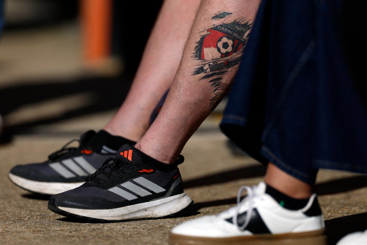 A Bournemouth fan with the club crest tattooed on his calf takes advantage of the sunshine to show off his ink.