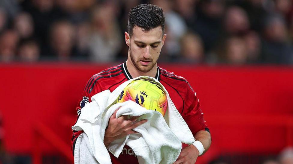 Diogo Dalot of Manchester United dries the ball with a towel during the Premier League match between Manchester United and West Ham United