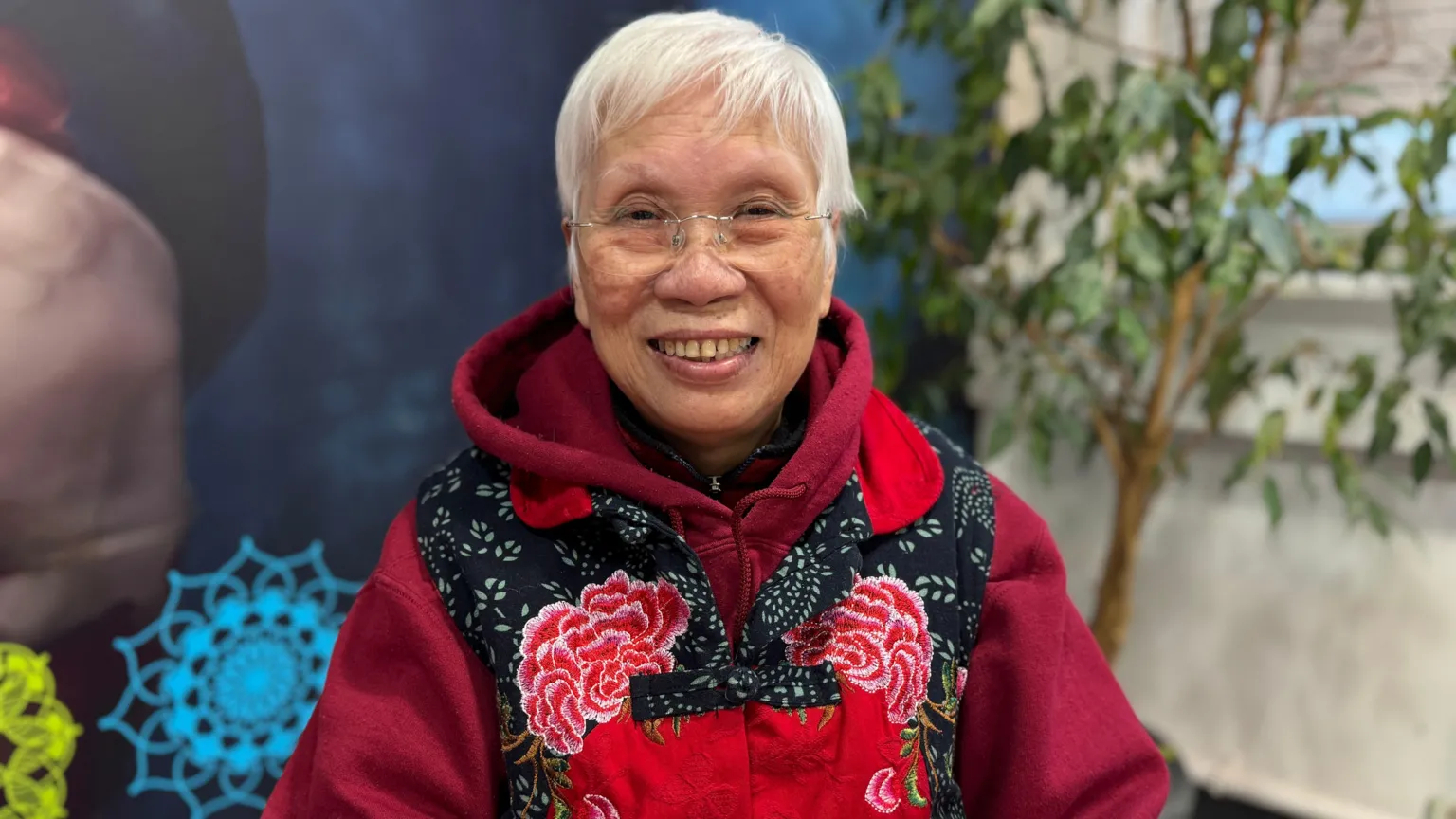 A woman with white hair and glasses smiling