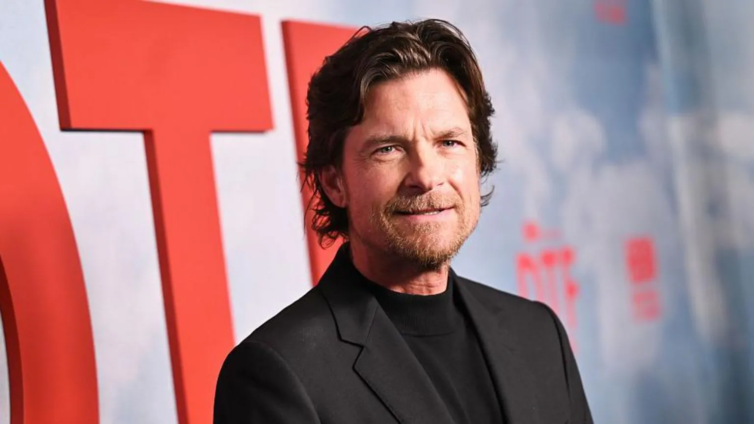  Jason Bateman, wearing a black top and black jacket