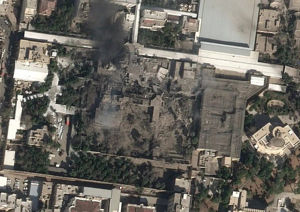A satellite image of apparently damaged, blackened buildings surrounded by upright buildings