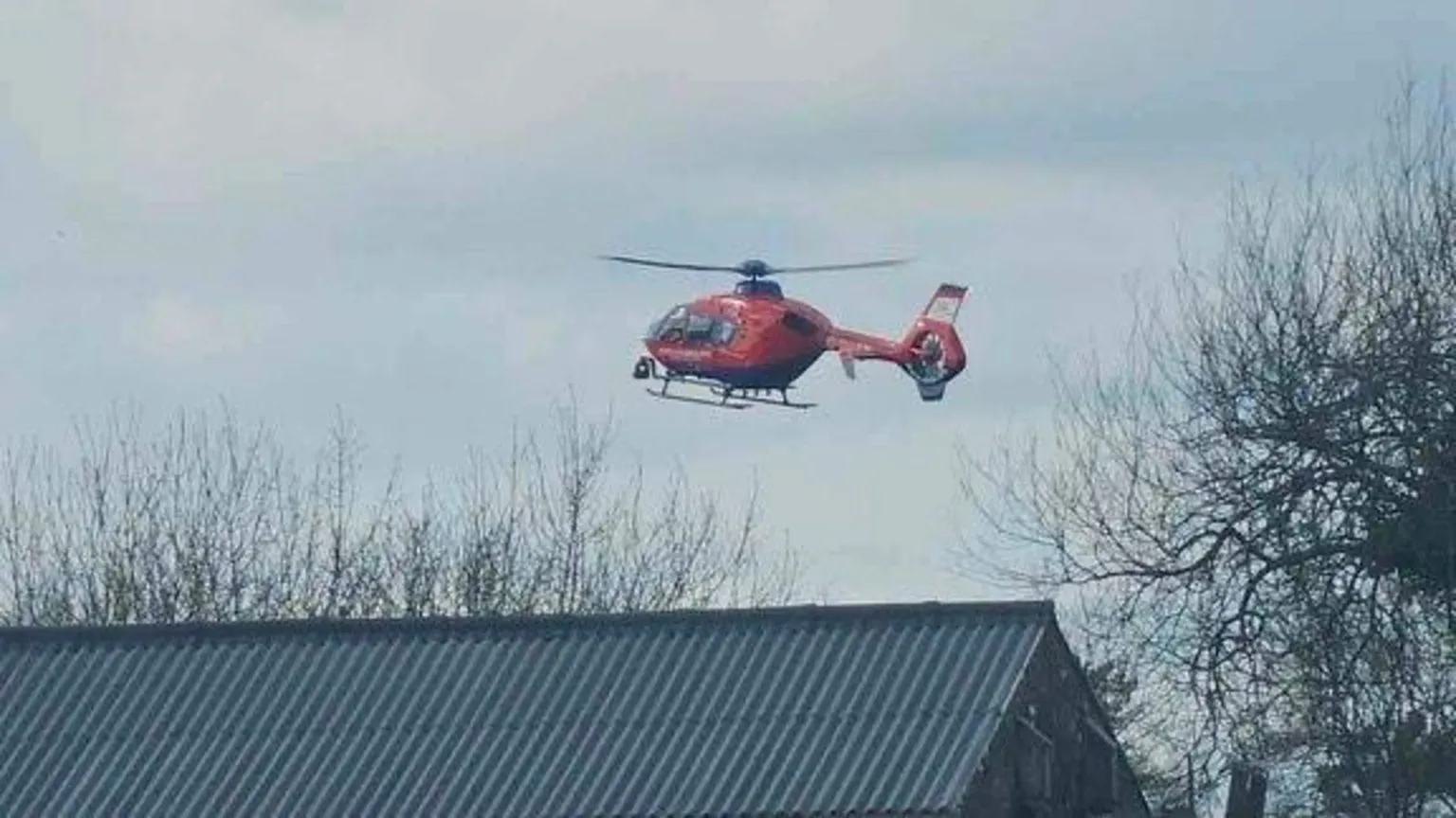 Rich Cliff A picture of an air ambulance leaving the scene. It is a red and blue helicopter.