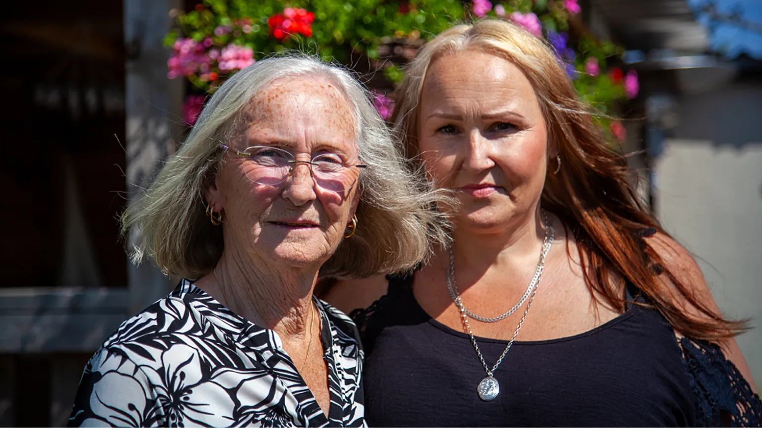 Yeti Television/BBC Cymru Wales Margaret Owen and her daughter Nicola pictured recently. Margaret has a grey bob and wears frameless glasses and a black and white patterned top and two pairs of gold hoop earrings. Nicola is in middle age and has long hair which is dyed light blonde at the roots and red elsewhere. She wears a black top with shoulder straps and shoulderless sleeves, and two silver chains. She is wearing make-up and hooped earrings. Both are looking at the camera and look serious.