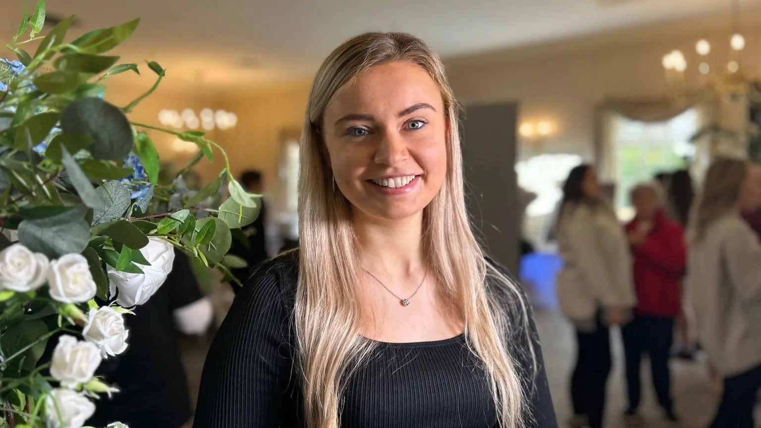 Meg Rolley is a young woman with long blonde hair and blue eyes. She is smiling and looking straight ahead. She is wearing a black top and a necklace with a fine chain and pendant.
