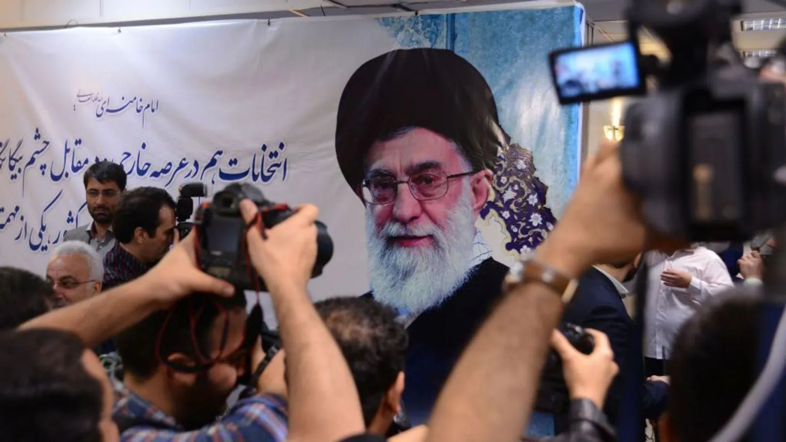 Hulton Archive via Ayatollah Khamenei shown on a poster. Supporters are photographing it.