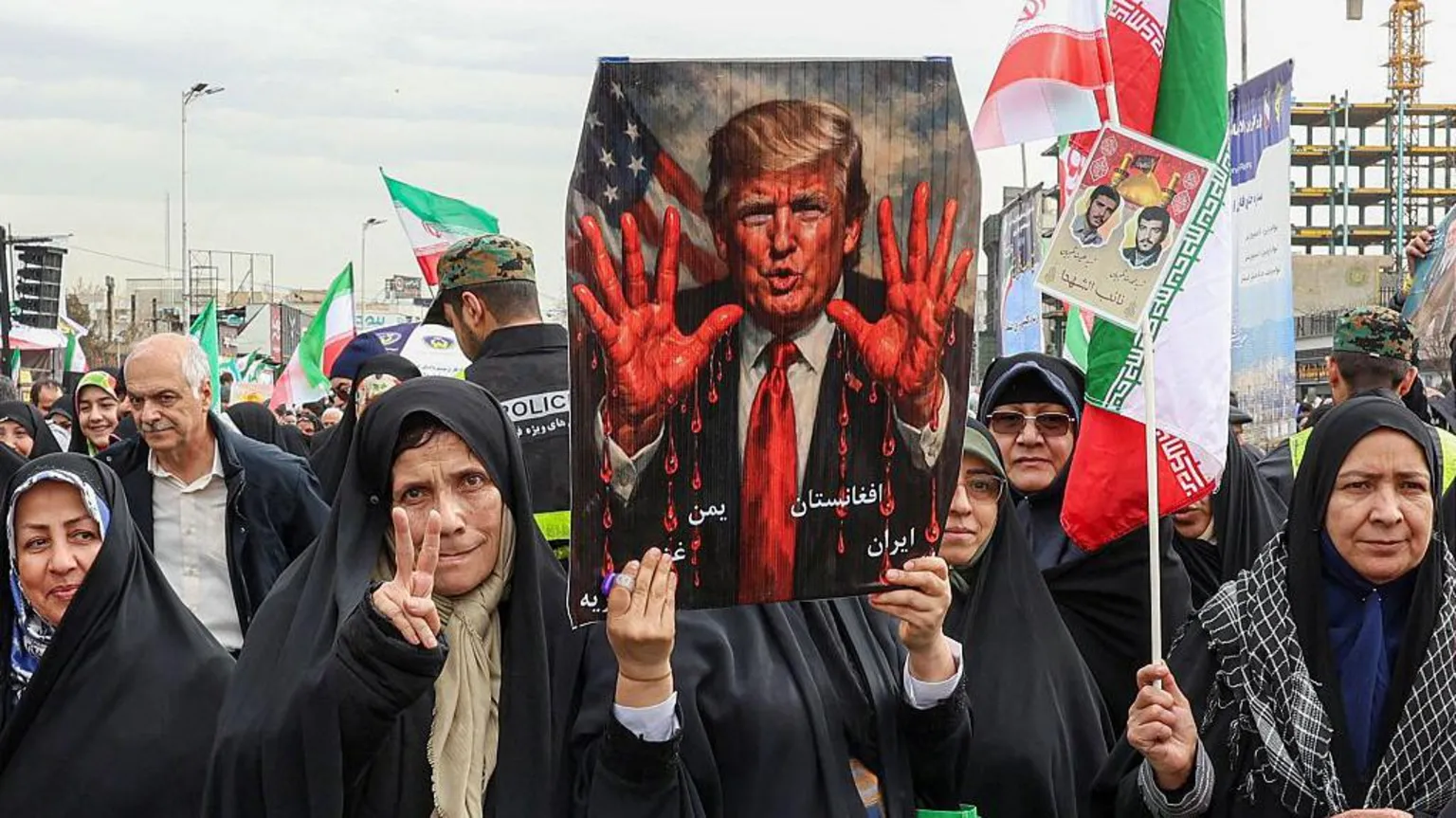 AFP via Supporters of the Iranian regime demonstrate against President Trump in 2026. They are holding up a poster showing the US President with bloodied hands