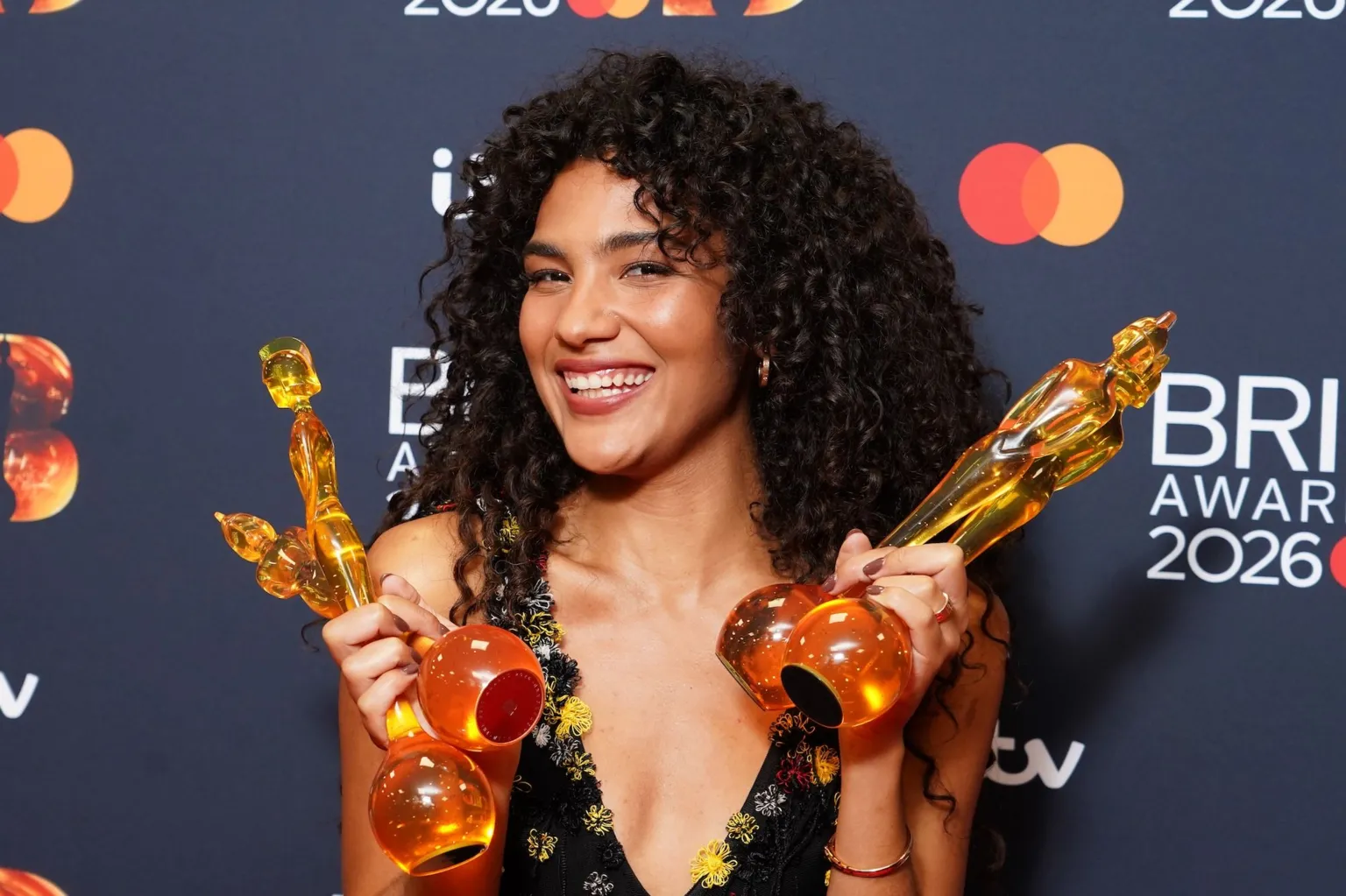  Olivia Dean beams as she holds up her four awards to the camera