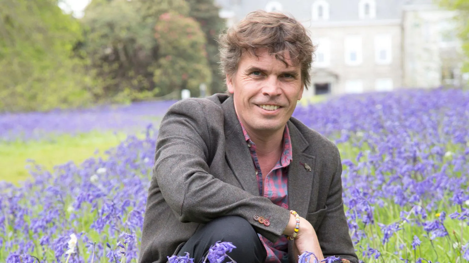 University of Exeter Dave Hodgson knelt in a field of purple flowers. 