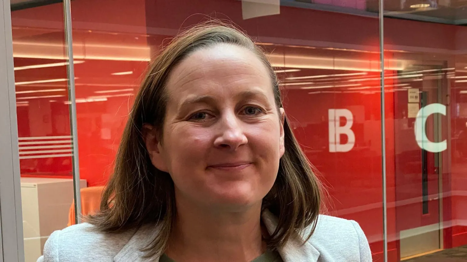 A smiling Camilla Marcus-Dew, co-founder of Amplify Goods, stood in front of a glass wall with the BBC logo reflected on it