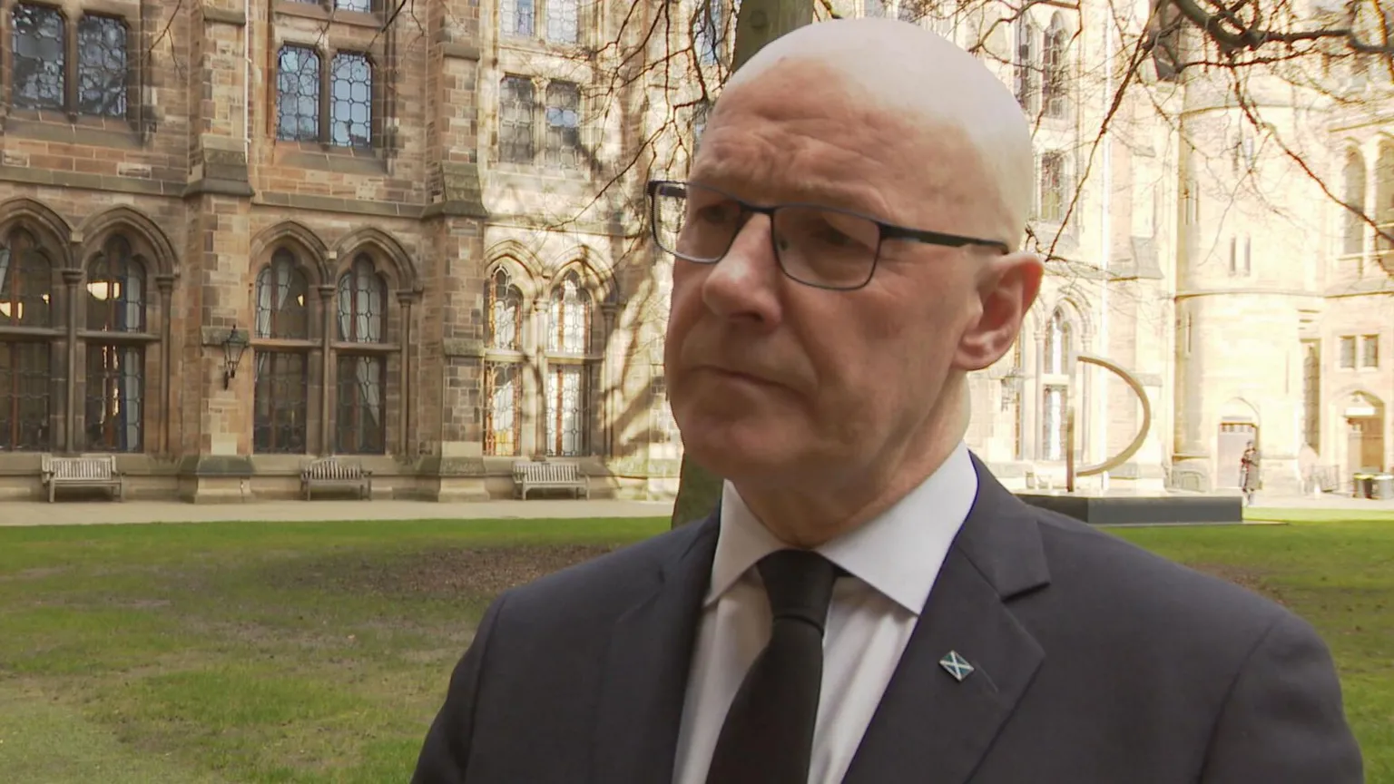 John Swinney wearing a dark suit and looking slightly off camera.