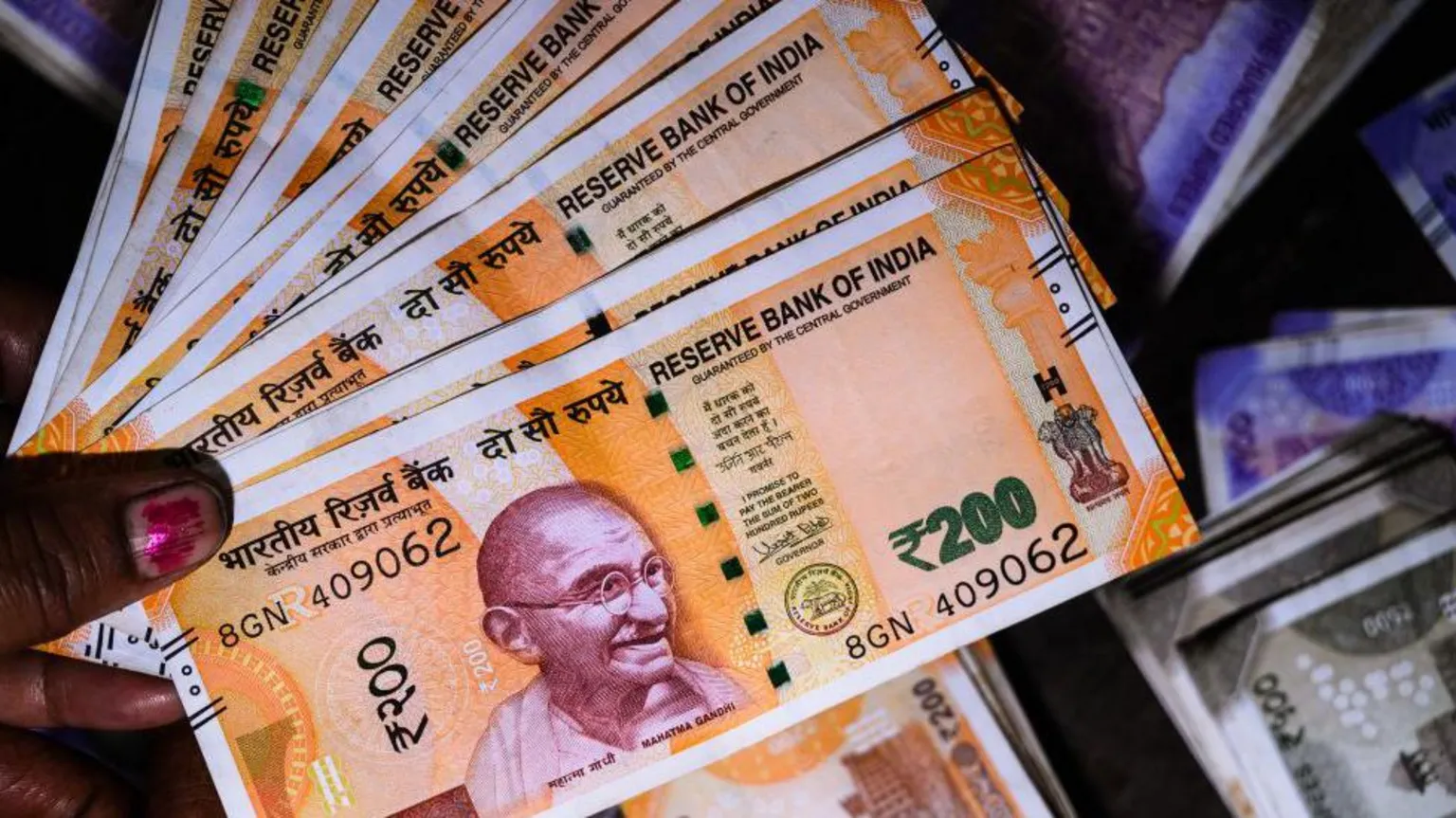 AFP via A woman holding rupee notes